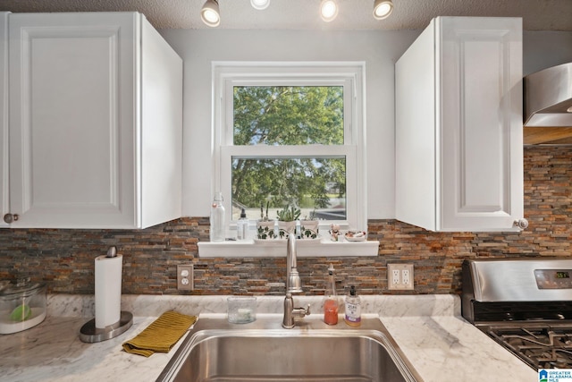 kitchen featuring a textured ceiling, gas range, and light stone counters