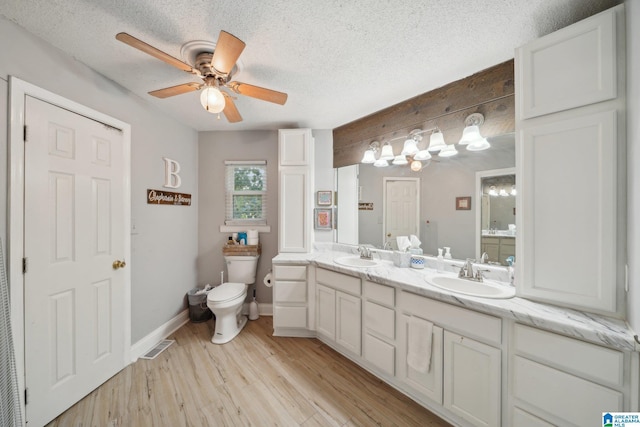 bathroom featuring a textured ceiling, ceiling fan, hardwood / wood-style flooring, toilet, and vanity