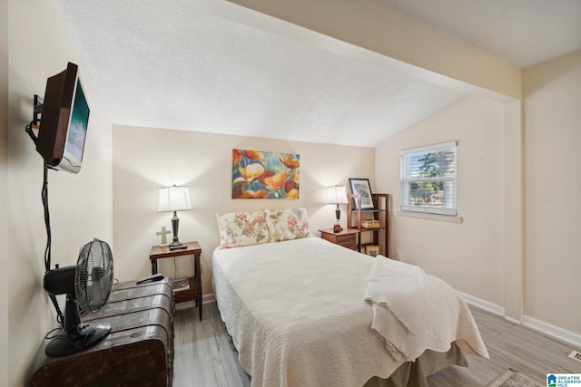 bedroom with vaulted ceiling with beams, a textured ceiling, and hardwood / wood-style flooring