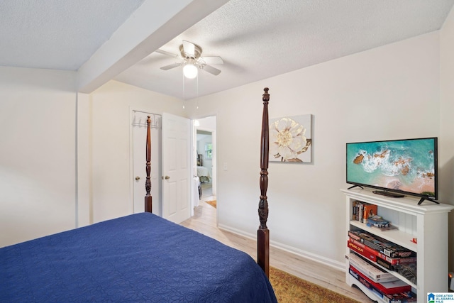 bedroom with ceiling fan, light wood-type flooring, and a textured ceiling