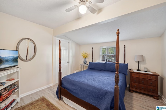 bedroom with a textured ceiling, ceiling fan, light hardwood / wood-style flooring, and vaulted ceiling with beams