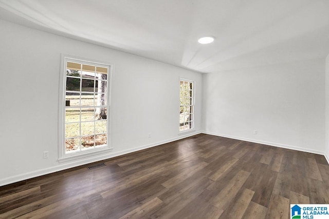 spare room featuring baseboards, visible vents, and dark wood finished floors