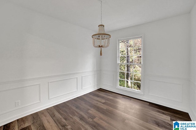 unfurnished dining area featuring a wainscoted wall, dark wood-style flooring, and visible vents