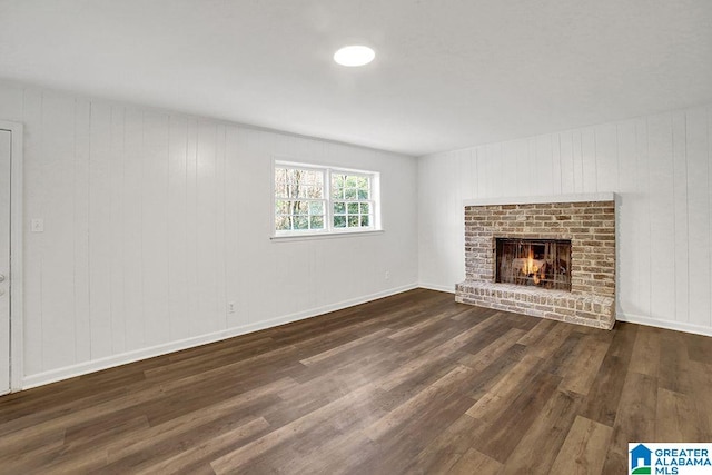 unfurnished living room featuring dark wood-style flooring, a fireplace, and baseboards