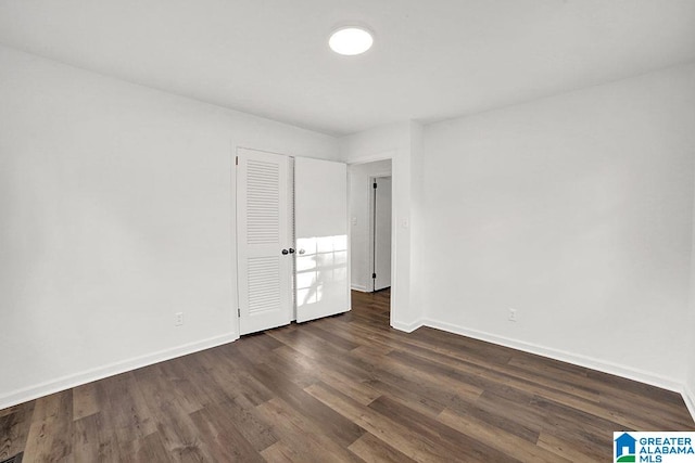 unfurnished bedroom with a closet, dark wood finished floors, and baseboards