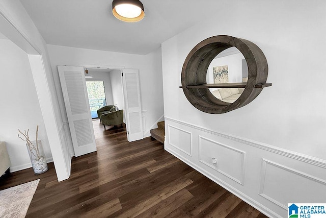 interior space featuring dark wood-type flooring, a wainscoted wall, and stairway