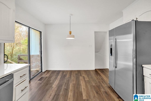 kitchen with dark wood finished floors, stainless steel appliances, light countertops, hanging light fixtures, and white cabinets