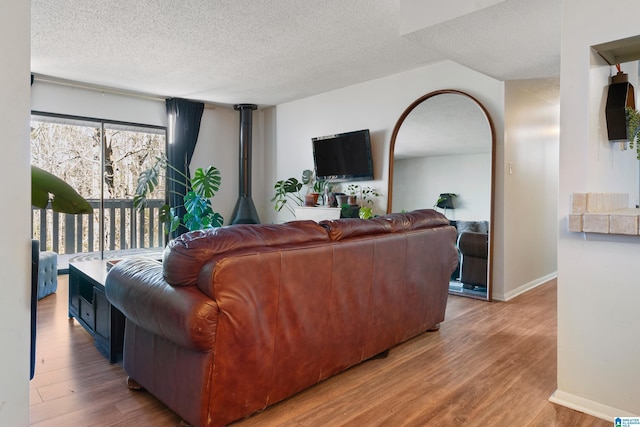 living room with a textured ceiling, light wood-type flooring, and a wood stove