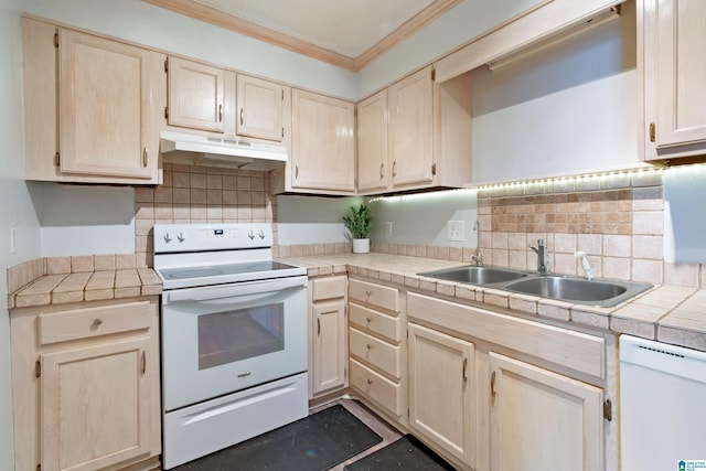 kitchen with sink, white appliances, crown molding, and tile counters