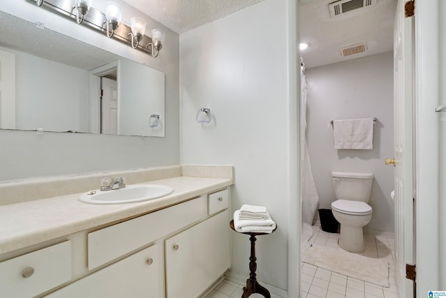 bathroom with toilet, tile patterned floors, vanity, and a textured ceiling