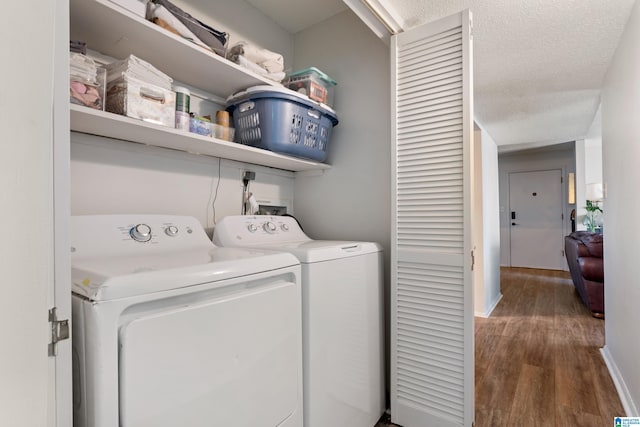 laundry area featuring dark wood-type flooring, a textured ceiling, and washer and clothes dryer