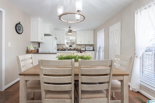 dining space with dark wood-type flooring and a notable chandelier