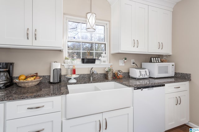 kitchen with sink, white cabinets, white appliances, hanging light fixtures, and dark stone counters