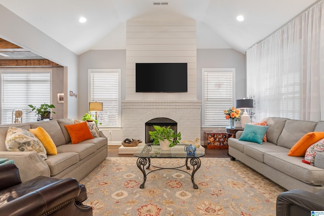 living room with hardwood / wood-style floors, vaulted ceiling, and a fireplace