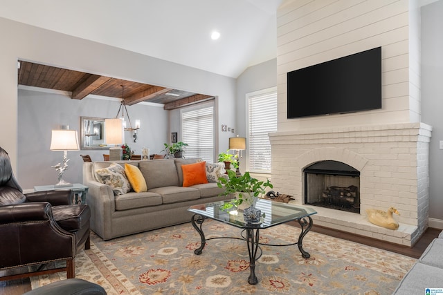 living room featuring a fireplace, wooden ceiling, vaulted ceiling with beams, and a notable chandelier