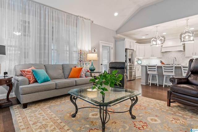 living room featuring sink, vaulted ceiling, and wood-type flooring