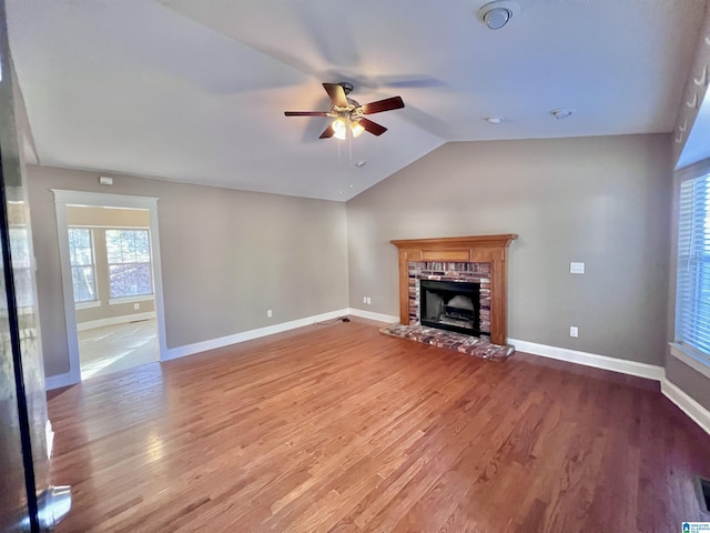 unfurnished living room with vaulted ceiling, a brick fireplace, ceiling fan, and hardwood / wood-style flooring