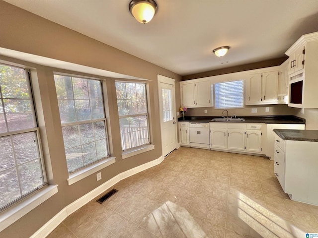 kitchen with white dishwasher, white cabinets, and sink