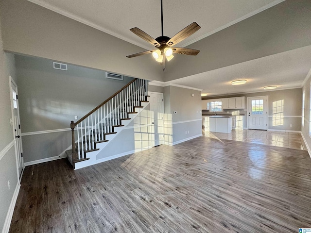 unfurnished living room featuring ornamental molding, ceiling fan, a textured ceiling, and hardwood / wood-style flooring