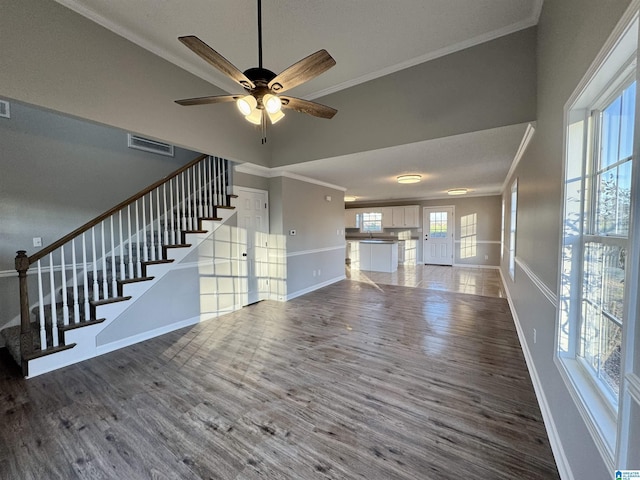 unfurnished living room with ceiling fan, crown molding, and dark wood-type flooring