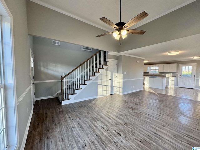 unfurnished living room with wood-type flooring, ceiling fan, and crown molding