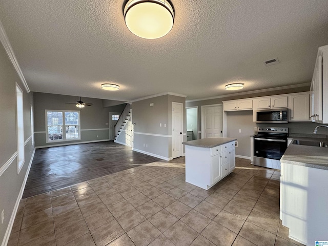 kitchen with stainless steel appliances, crown molding, light tile patterned floors, white cabinets, and sink