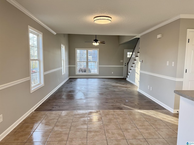 spare room featuring a textured ceiling, ceiling fan, light tile patterned floors, and crown molding