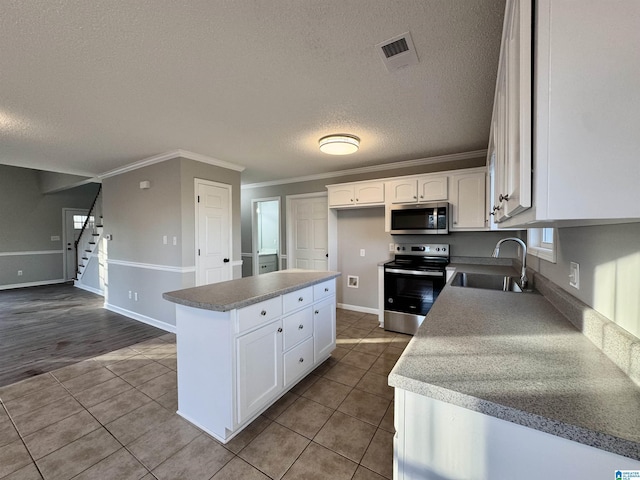 kitchen featuring a center island, tile patterned floors, white cabinetry, appliances with stainless steel finishes, and sink