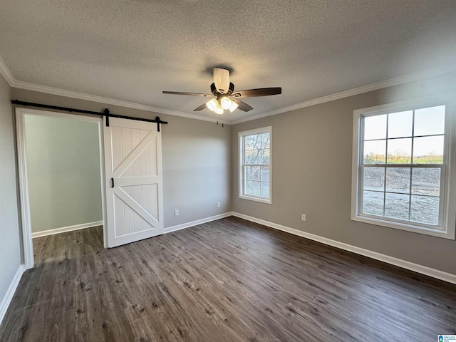 unfurnished bedroom featuring ceiling fan, ornamental molding, a barn door, and dark hardwood / wood-style floors