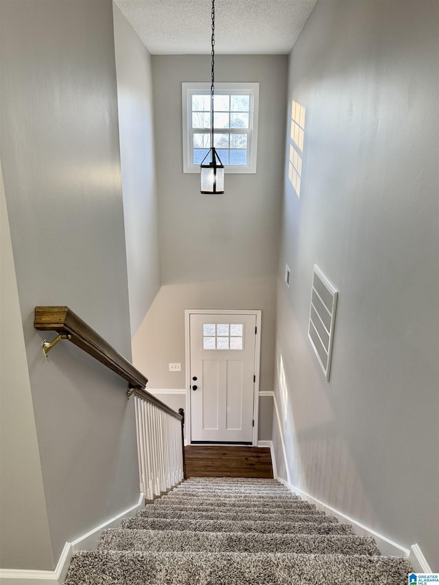 stairs with carpet floors and a textured ceiling