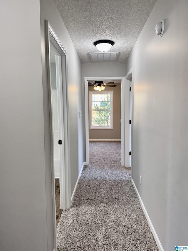 corridor featuring a textured ceiling and light carpet