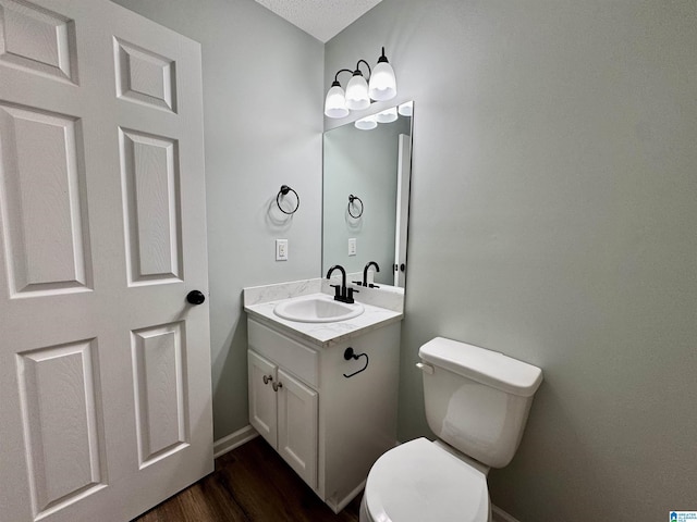 bathroom with toilet, vanity, a textured ceiling, and hardwood / wood-style floors