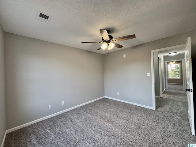 spare room with a textured ceiling, ceiling fan, and carpet