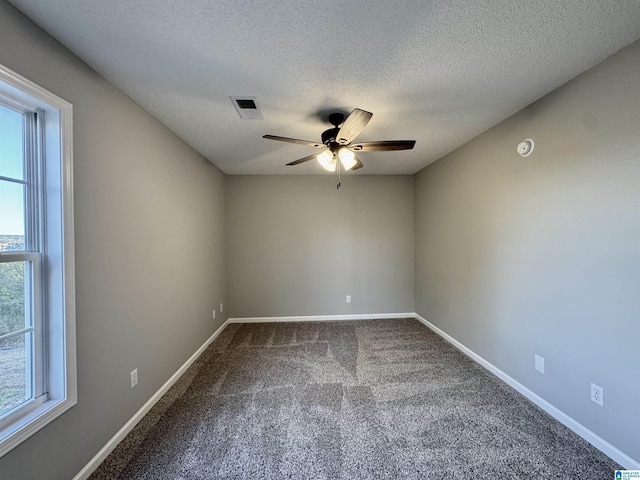 carpeted empty room with a textured ceiling, ceiling fan, and a wealth of natural light