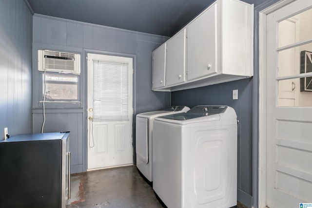 washroom featuring washer and clothes dryer, cabinets, and a wall mounted AC