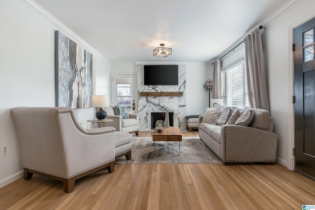 living room with crown molding, plenty of natural light, light hardwood / wood-style flooring, and a stone fireplace