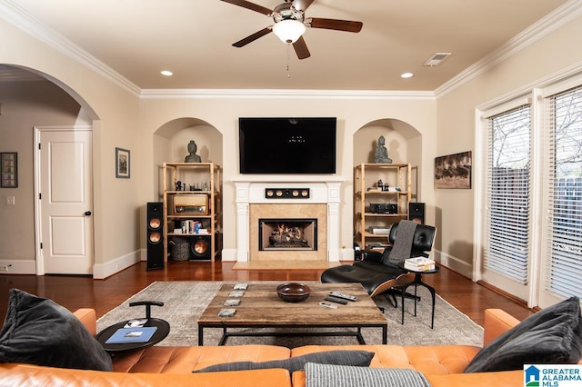 living room with ceiling fan, dark hardwood / wood-style flooring, ornamental molding, and a fireplace