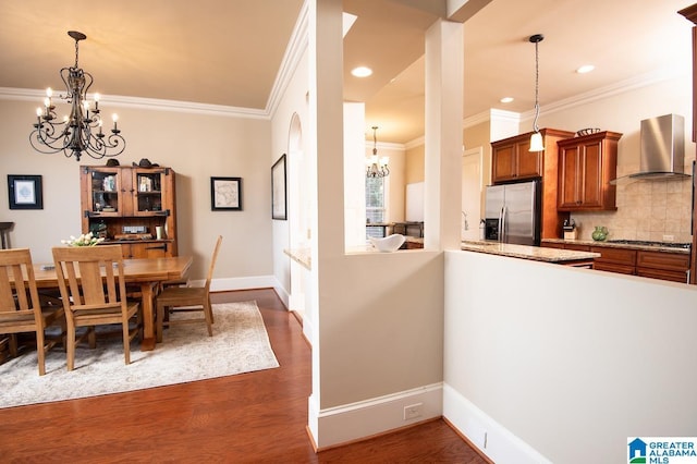 dining area with crown molding, dark wood-type flooring, and an inviting chandelier