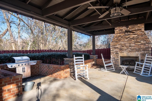 view of patio featuring ceiling fan, exterior bar, grilling area, and an outdoor stone fireplace