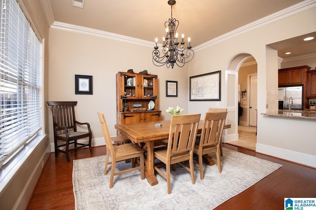 dining space featuring dark hardwood / wood-style flooring, ornamental molding, and a notable chandelier