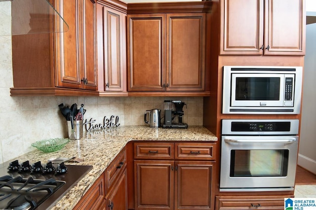 kitchen with decorative backsplash, light stone countertops, and stainless steel appliances