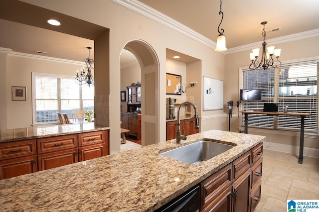 kitchen with light stone countertops, sink, ornamental molding, and a notable chandelier