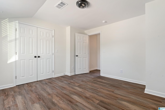 unfurnished bedroom with dark hardwood / wood-style flooring, a closet, and lofted ceiling