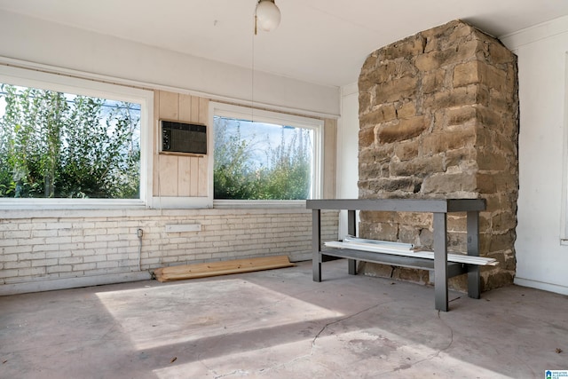 miscellaneous room with concrete flooring, plenty of natural light, and brick wall