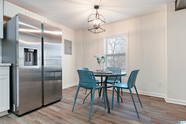 dining space with electric panel, light hardwood / wood-style flooring, and an inviting chandelier