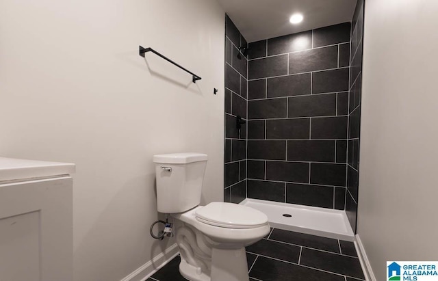 bathroom with toilet, tiled shower, and tile patterned floors