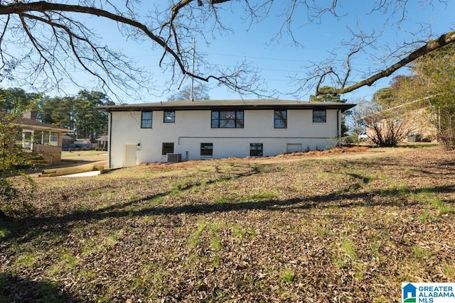 back of property with central air condition unit and a lawn