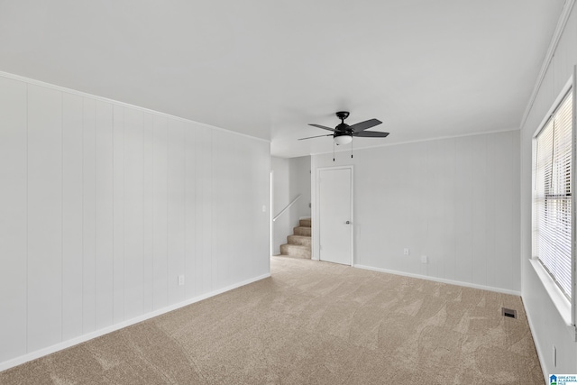 carpeted spare room featuring ceiling fan and ornamental molding