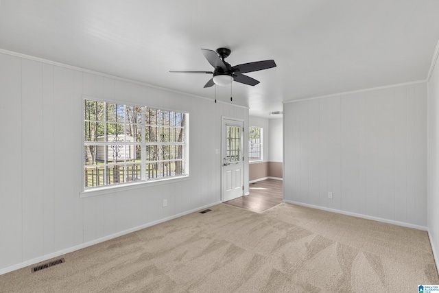 carpeted spare room with ceiling fan and ornamental molding