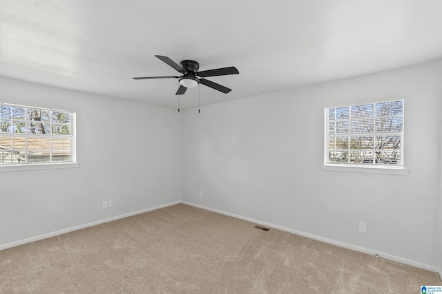 empty room with ceiling fan, a wealth of natural light, and light carpet